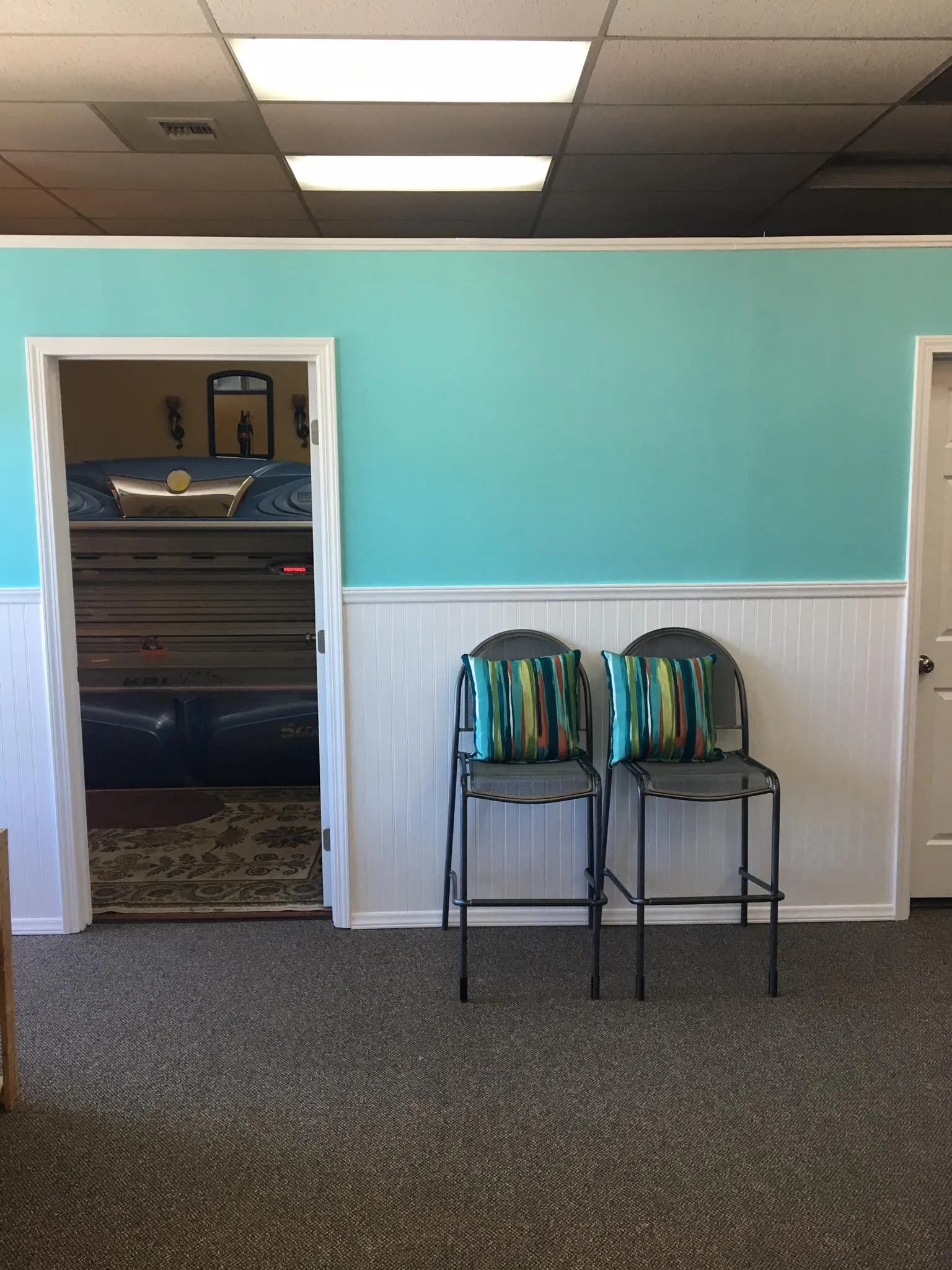The lobby's aqua walls and white beadboard, with a door open on a tanning bed